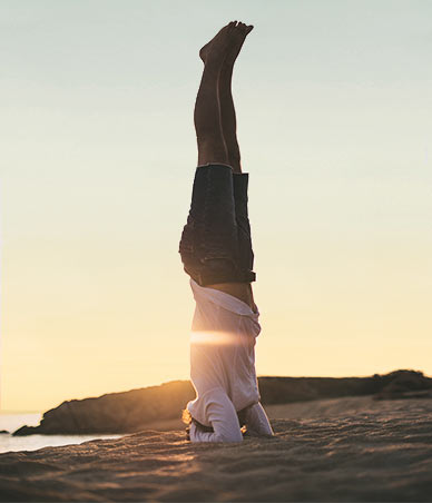 Mann macht Yogaübungen am Strand.