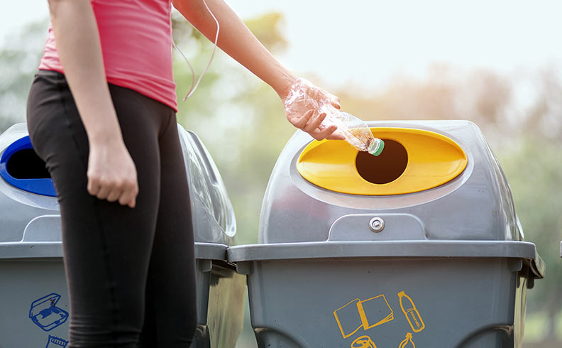 Frau wirft Plastikflasche in den Mülleimer