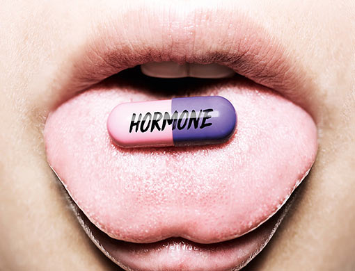 Nahaufnahme einer Hormon-Tablette, die auf einer ausgestreckten Zunge liegt